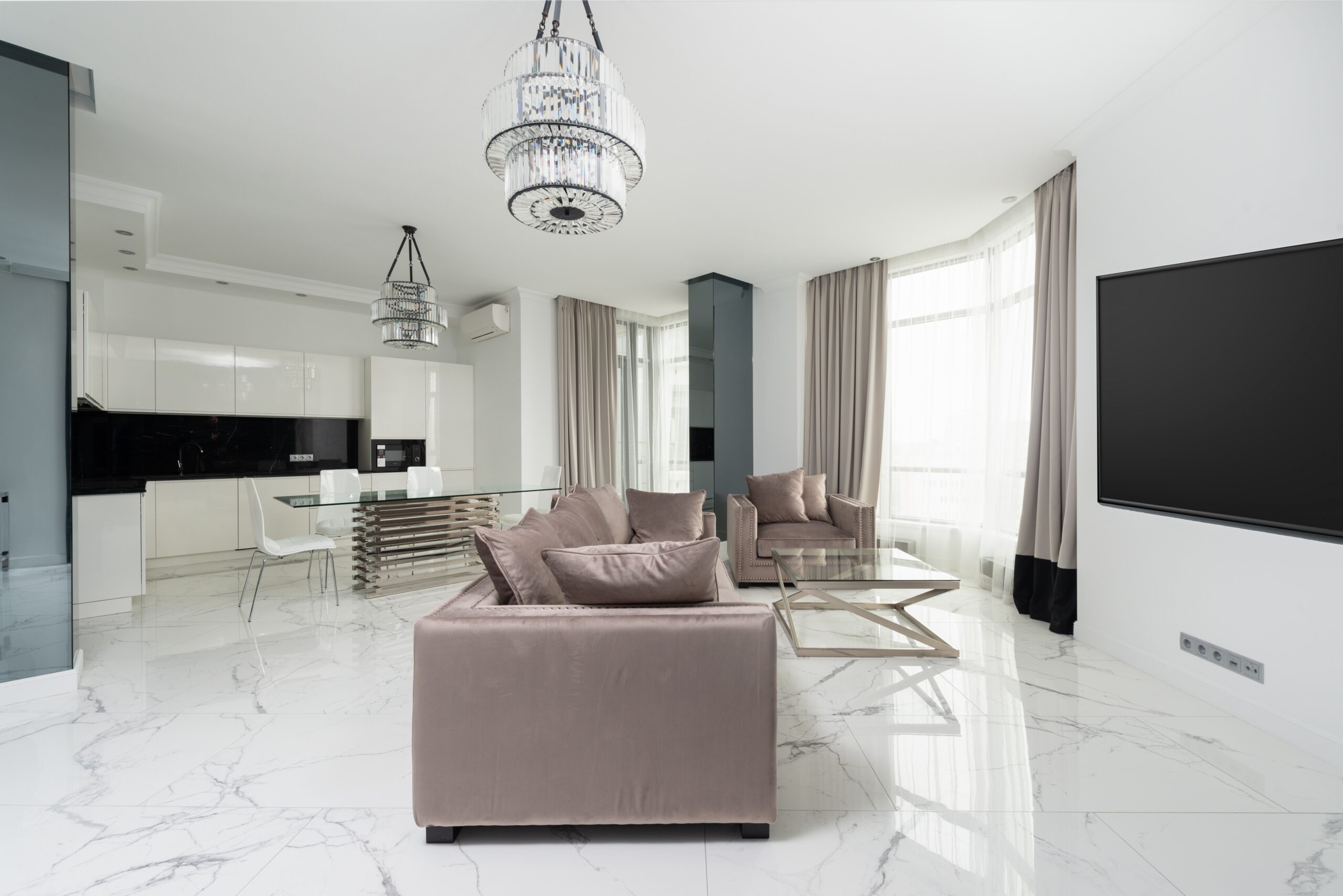 Nowoczesny salon z jasnymi ścianami, eleganckimi meblami i dużymi oknami, tworzący przytulną atmosferę