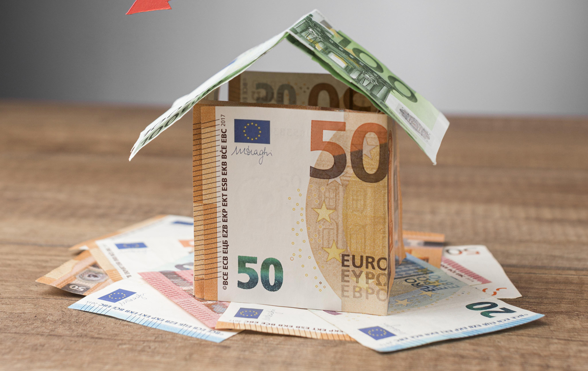 Model domu z banknotów euro na drewnianym stole, symbolizujący kwestie finansowe i zwrot kaucji