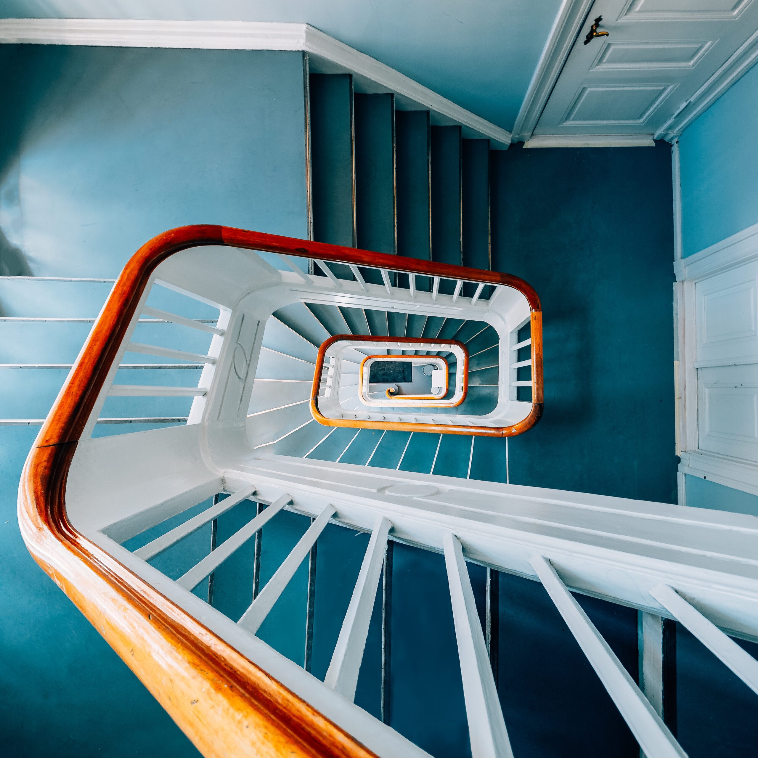 Widok z góry nowoczesnych spiralnych schodów w jasnym wnętrzu, z wyraźnymi detalami balustrady